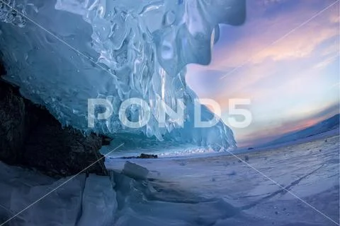 Sunset in a cave grotto with icicles in the winter on Olkhon Island, Lake Baikal Stock Photos