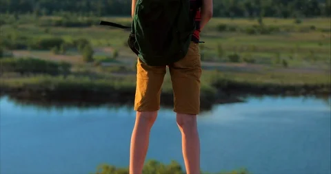 At Sunset Child in a Red Shirt a Backpack on His Back, Reaching to the Top on a Stock Footage 108772715