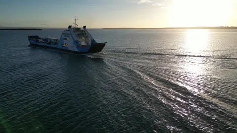 Sunset circling shot of vehicle ferry sailing away from dock towards to horizon Stock Footage 281146161