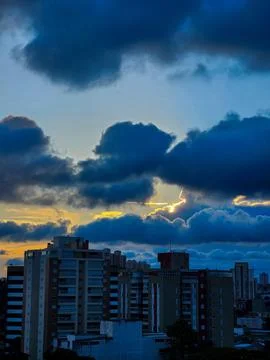 A sunset in a city. Building in the background, dark sky with heavy clouds an Stock Photos