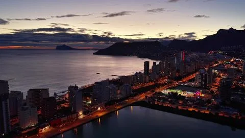 Sunset cityscape overview. Dusk view of oceanfront city with illumination a.. Stock Photos