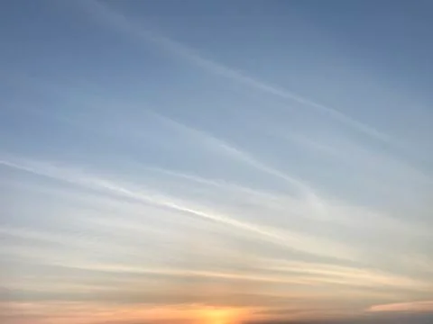 Sunset with clear smooth blue sky and white line clouds Stock Photos