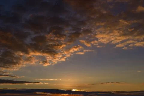 Sunset clouds across panoramic sky. Sunset sky above layered clouds. Dramatic Stock Photos