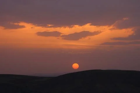 A sunset with clouds and a orange sun setting in the sky. Stock-Fotos