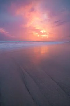 Sunset clouds and waves on empty beach Stock Photos