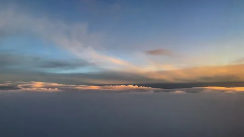 Sunset clouds casting golden light above horizon line. 動画素材 287310315