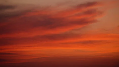 Sunset clouds creating a gradient of fiery red, orange, and golden hues across Stock Footage 325224044