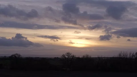 Sunset clouds crossing the sky with silhoutted trees &amp; hills timelapse Stock-Footage 262896378