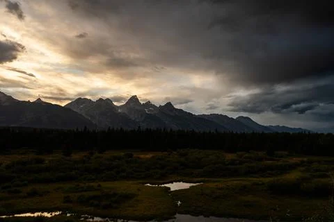 Sunset clouds drift over beautiful mountain wilderness and rivers, filling th Stock Photos
