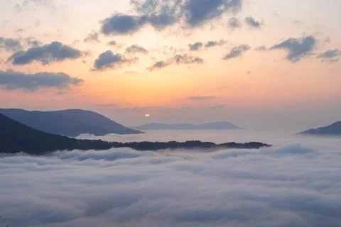 Sunset with clouds floating under the mountain tops in summer. Panorama of mo Stock Photos