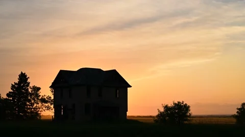 Sunset clouds moving with an abandoned house silhouette in the foreground.  Stock Footage 156970535