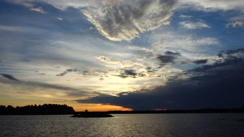Sunset with clouds over calm lake with an island Video stock 156066376