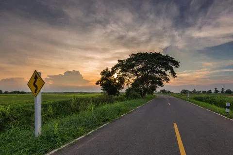 Sunset in clouds with sunrays over road to horizon Stock Photos