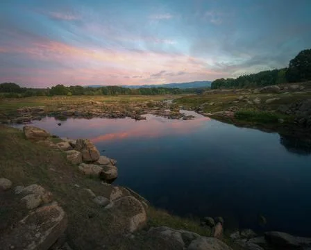 Sunset cloudscape reflected in the calm waters of the river Stock Photos