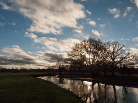 Sunset cloudy blue sky trees silhouette lake river dedham Stock Photos