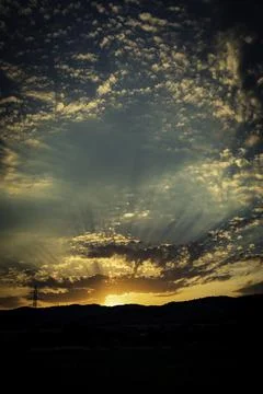 Sunset on a cloudy day with sun rays Stock Photos