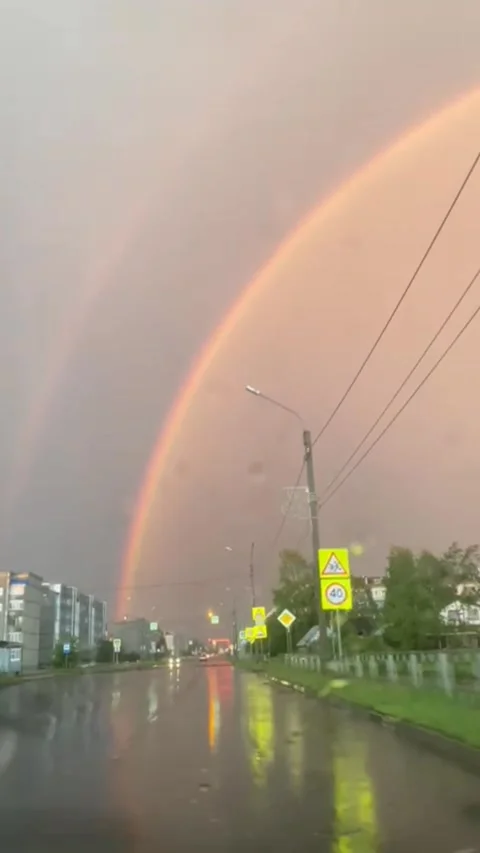 At sunset on a cloudy, rainy evening, a beautiful orange rainbow can be seen thr Stock Footage 313608041