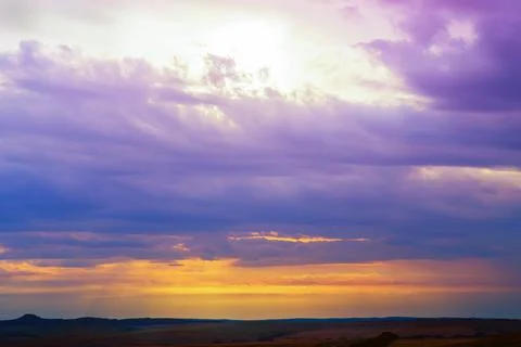 Sunset in cloudy sky over field Stock Photos