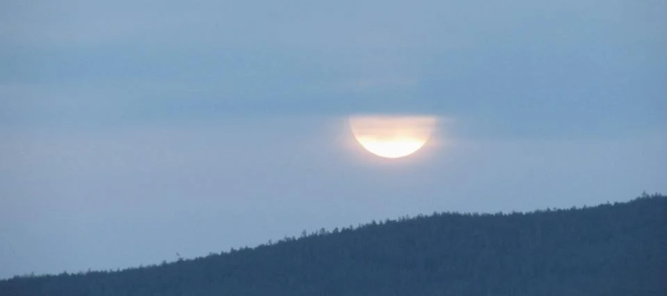 Sunset in cloudy sky over forested hills. Stock Photos