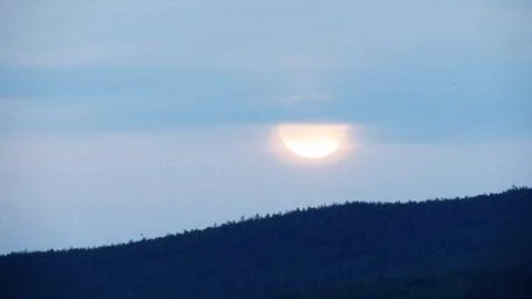 Sunset in cloudy sky over forested hills. Stock Photos