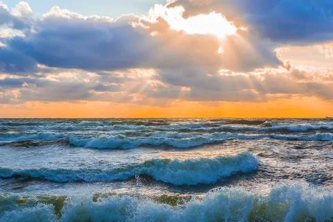 Sunset in the cloudy sky over the stormy sea Stock Photos