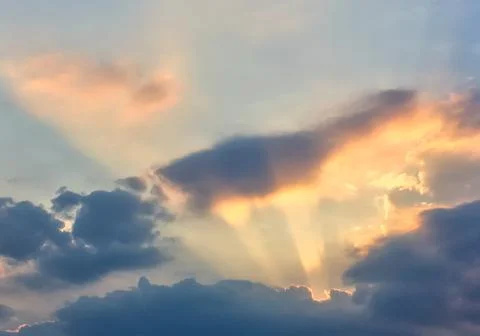 Sunset on cloudy sky. Rays of light shine up to the sky through clouds. Stock Photos