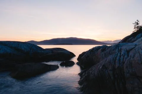 Sunset on coast with cliffs and mountains in background Stock Photos