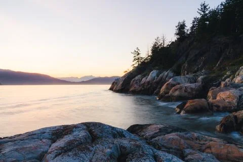 Sunset on coast with cliffs and mountains in background Stock Photos