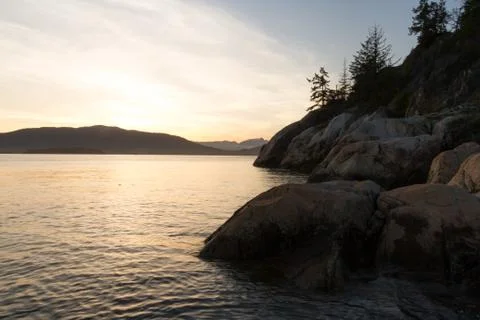Sunset on coast with cliffs and mountains in background Stock Photos