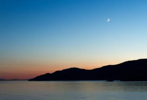 Sunset on coast with cliffs and mountains in background Stock Photos