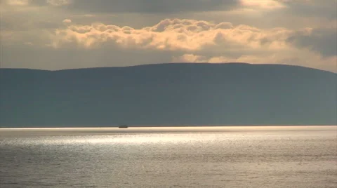 Sunset colored clouds and reflection on water with mountain silhouette Stock Footage 39986757