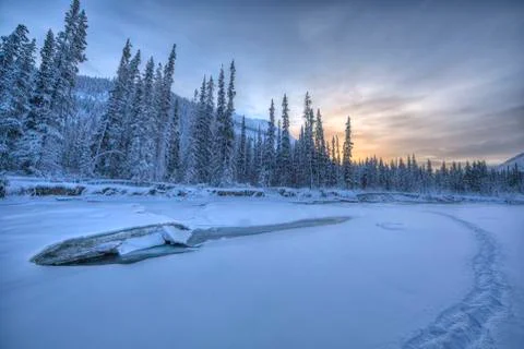 Sunset colours in the sky over the mostly frozen Wheaton River. Walking tracks Stock Photos