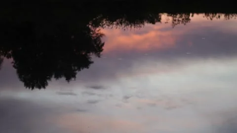 Sunset dark cloudy colourful sky reflects in still evening dark water of lake Stock Footage 131993611