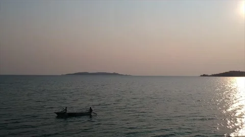 Sunset on deep blue waters of the lake with two men on a traditional boat, Makor Stock Footage 147029675