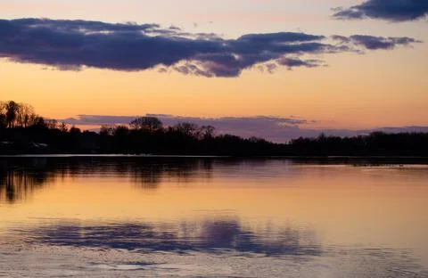 Sunset on Dnieper river. Beautiful dramatic cloudy sky and tree silhouettes r Stock Photos