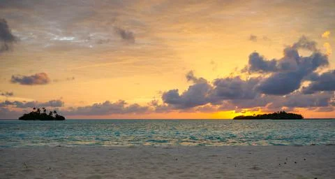 Sunset with dramatic clouds on the tropical beach. Panorama with two uninhabi Stock Photos