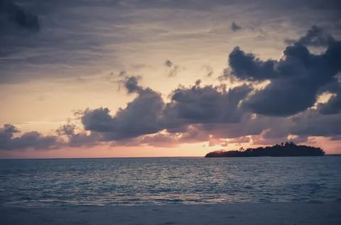 Sunset with dramatic clouds on the tropical beach. Panorama with two uninhabi Stock Photos