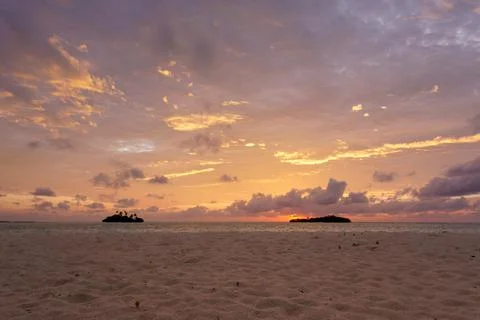 Sunset with dramatic clouds on the tropical beach. Panorama with two uninhabi Stock Photos