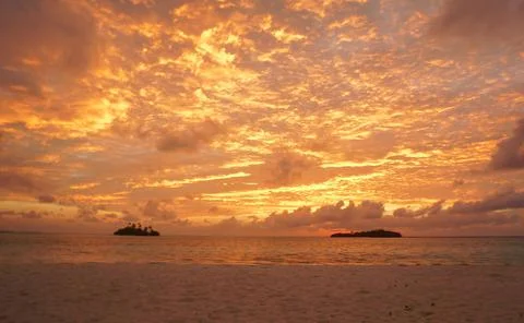 Sunset with dramatic clouds on the tropical beach. Panorama with two uninhabi Stock Photos
