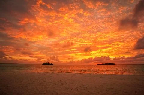 Sunset with dramatic clouds on the tropical beach. Panorama with two uninhabi Stock Photos