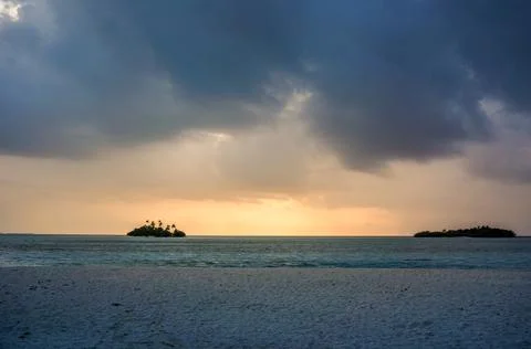 Sunset with dramatic clouds on the tropical beach. Panorama with two uninhabi Stock Photos