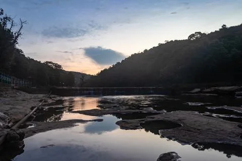 Sunset dramatic orange sky with water reflection and mountain shadow at morni 스톡 사진