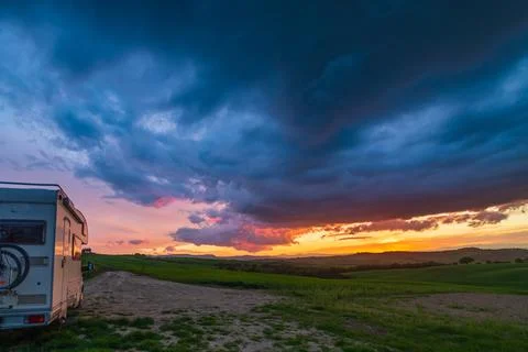 Sunset dramatic sky over camper van in Orcia Valley, Tuscany, Italy. Epic clo Stock Photos