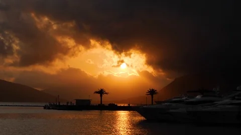 Sunset in dramatic stormy sky over sea with a quay. Water reflects bright sun 스톡 동영상 83123038