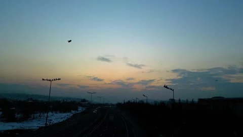 At sunset, a drone flying with crows over the road 動画素材 294798268