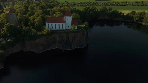 Sunset drone orbit of Wehrkirche Beucha on rock cliff above lake near Leipzig Video stock 309965655
