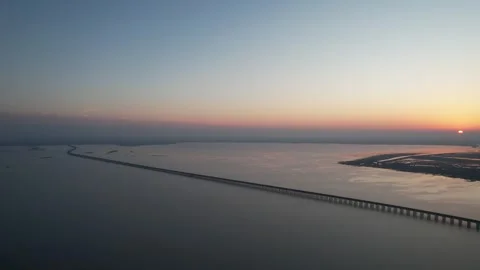 Sunset drone view of sea bridge and glowing horizon over open water in China Stock Footage 337759183