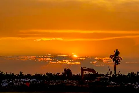 Sunset the evening light through the clouds and the shadow of Backhoe loaders Stock Photos