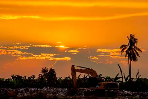 Sunset the evening light through the clouds and the shadow of Backhoe loaders Stock Photos