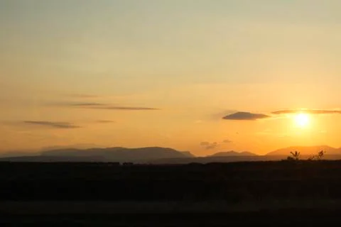 Sunset on a field with mountains in backround Stock Photos